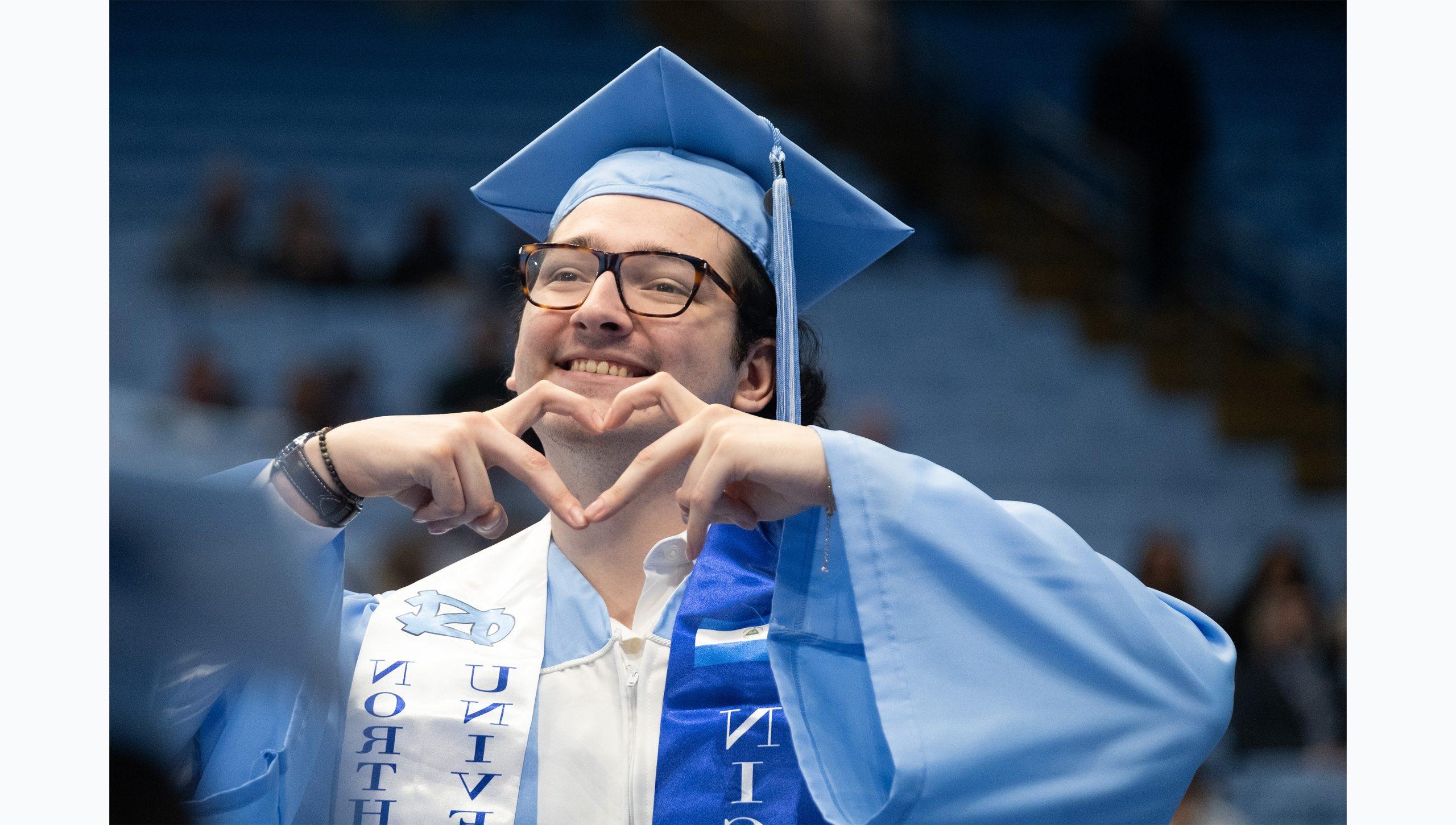 A graduate forming a heart shape with his hands at U.N.C. Chapel Hill's Winter Commencement.