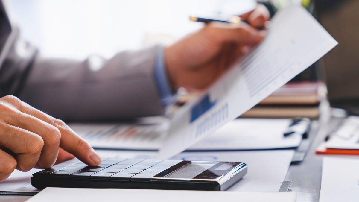 Person working at desk with spreadsheet and calculator.